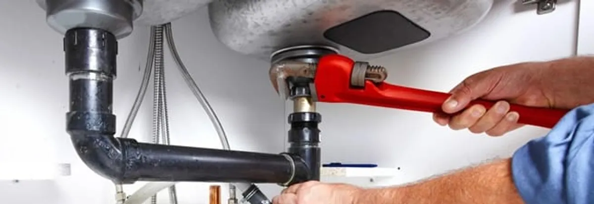Garbage disposal repair technician tightening the sink drain and disposal connection in Eugene, OR