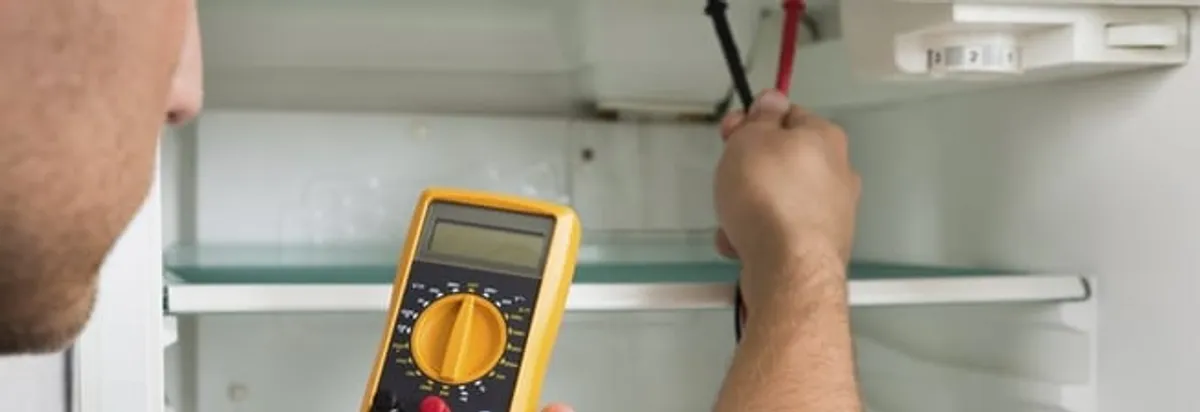 Refrigerator repair technician testing electrical components with a multimeter in Eugene, OR