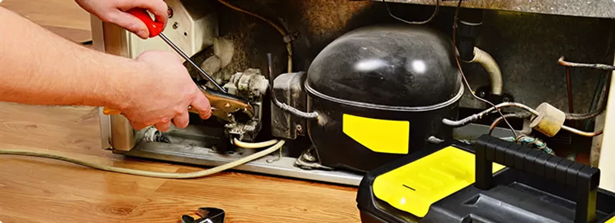 Refrigerator repair technician fixing the compressor and wiring in Eugene, OR
